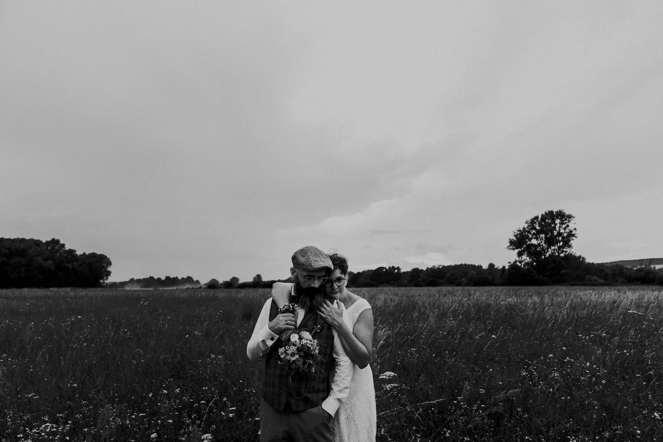 Brautpaar steht auf Feld für Hochzeitsfoto. Hochzeitsbilder von Hochzeitsfotograf aus Würzburg