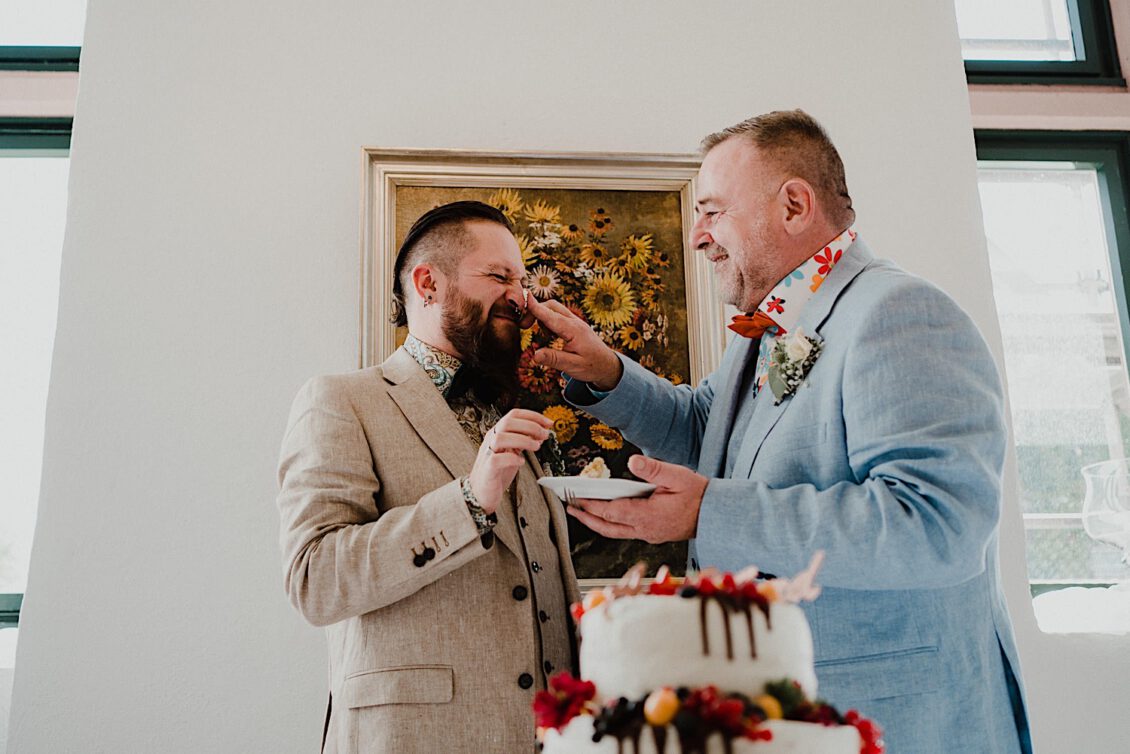 30_Hochzeitsfotograf-Wuerzburg-24_Das Hochzeitspaar schneidet die Hochzeitstorte an bei schwulen Hochzeit in der Burg Konradsheim bei Ko?n. Hochzeitsbild vom Hochzeitsfotograf Axel Link